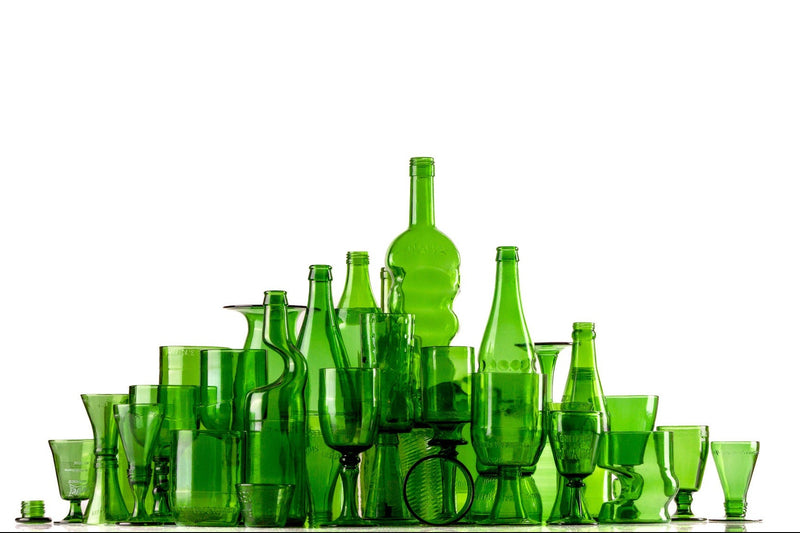 Collection of green glass bottles and glasses on a white background